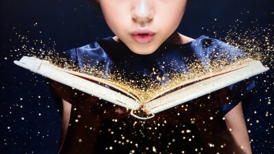 Person blowing sparkles off a book